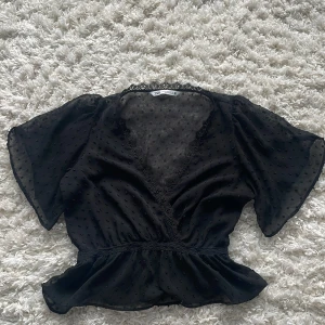 Svart blus med spets från Zara!! - Supersöt svart blus från Zara med v-ringning och spetsdetaljer. Tunn och lite genomskinlig. Passar perfekt med en kofta över nu i höst eller i sommar. Insydda prickar och lätt volang nertill. Korta, vida ärmar och elastisk midja ger en snygg siluett. Använd bara några få gånger av mig. Skicka dm om ni är intresserade!!!❤️❤️🍁🍁🍁