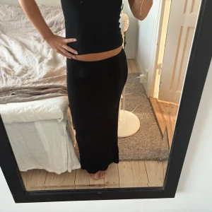 Långkjol  - Säljer en svart ribbad långkjol från Weekday i storlek XS. Kjolen är figurnära med en slits baktill. 