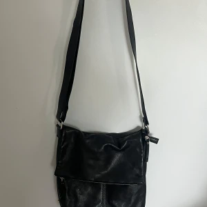 Svart axelväska i skinn från Don Donna - Vintage svart axelväska från Don Donna i äkta skinn med bred axelrem som är justerbar. Har flera fack: ett på baksidan och tre stycken inne i väskan. Silvriga detaljer. Använd några gånger för länge sedan men finns inga defekter och väskan känns fortfarande fräsch och är i mycket bra skick. Hör av dig om du har fler frågor eller vill diskutera pris🥰