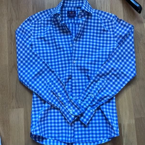 Blårutig skjorta från La Chemise - Snygg blårutig skjorta från La Chemise i slim fit-modell. Skjortan har klassisk krage, långa ärmar och knäppning framtill. Tillverkad i bomull för en skön känsla och stilren look. Perfekt för dig som gillar en fräsch och modern stil. I princip oanvänd. Pris kan diskuteras.
