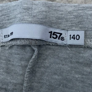 Grå mjukisbyxor från lager 157, stl 140 - Grå mjukisbyxor från lager 157 i storlek 140. Byxorna har en enkel och clean look med smal passform och resår i midjan. Perfekta för chill dagar eller när du vill ha det bekvämt. Tillverkade i mjukt material som känns skönt mot huden.