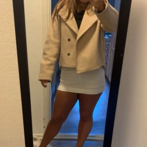 Beige kappa - Snygg beige kappa med stora slag och dubbelknäppning framtill. Jackan är croppad och har en stilren, boxig passform som passar perfekt till höst och vår. Tillverkad i ett mjukt material som känns lyxigt och trendigt.