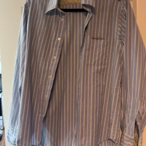 Blåvit randig skjorta från Replay - Klassisk blå skjorta med vita ränder från Replay. Skjortan har lång ärm, bröstficka och knäppning framtill. Perfekt för en stilren och avslappnad look.