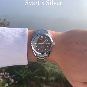 Svart och silver klocka från Doventi - Stilren klocka från Doventi med svart urtavla och silverfärgat armband i metall. Klockan har tydliga index, datumvisning och klassisk rund form. Perfekt accessoar för dig som gillar en clean och modern look.