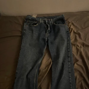 Levi's 501 blå jeans straight fit - Klassiska Levi's 501 jeans i en mörkblå tvätt. Rak passform med fem fickor och knappgylf. Ikonisk läderpatch bak i midjan och röd Levi's-tagg på bakfickan. Perfekta för dig som gillar en tidlös och avslappnad look.