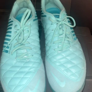 Nike Hyperfuse turkosa fotbollsskor/inomhusskor  - Snygga turkosa Nike Hyperfuse fotbollsskor med quiltad ovandel och coola ränder på sidorna. Skorna har snörning, låg profil och vit Nike-logga. Perfekta för dig som vill sticka ut på planen med stil och komfort. Pris kan diskuteras! 