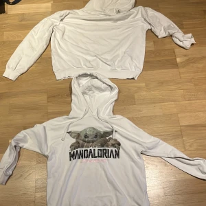Vit Mandalorian hoodie med Baby Yoda - Säljer en vit hoodie med tryck av Baby Yoda och texten 'The Mandalorian Star Wars' på bröstet. Tröjan har huva med snörning och långa ärmar. Perfekt för dig som älskar Star Wars och vill ha en bekväm och snygg tröja.Den har en pytteliten fläck på framsidan som man inte ser om man inte är på nära håll och vet att den är där