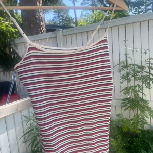  linnetopp från Primark - Säljer en stretchig linnetopp från Primark med tunna, justerbara axelband. Toppen har smala ränder i vitt, rött och mörkblått och är 44 cm lång. 