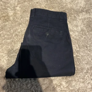 Svarta slim fit chinos från H&M - Svarta chinos från H&M i slim fit-modell. Byxorna har klassisk design med snedställda fickor fram, en bakficka med knapp och hällor för bälte. Perfekta för en clean och stilren look. Materialet är mjukt och bekvämt bomullstyg. Använd 10 gånger max 