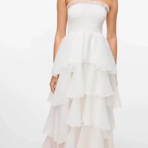 Vit volangklänning med bar axel - Superfin långklänning med volanger från Vero Moda. Aldrig använd, endast testad. Storlek M men passar mig som vanligtvis har xs/s. Har tyvärr inte fått tillfälle att använda denna men är så otroligt fin så hoppas därav kunna sälja den vidare💓köpt för: 1200kr💓