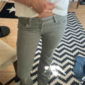 Gråa bootcut byxor från Nelly - Snygga gröna low waist bootcut byxor från Nelly med vita kontrastsömmar och dubbla knappar i midjan. Jeansen är använda fåtal gånger och är som nya! Storlek 34! Nypris 700kr säljer för 470kr! Pris kan diskuteras!