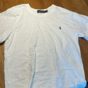 Vit t-shirt från Polo Ralph Lauren - Vit klassisk t-shirt från Polo Ralph Lauren med broderad logga på bröstet. T-shirten är i mjuk bomull och har rund hals och korta ärmar. Perfekt basic-plagg med stilren design och skön passform. Pris kan diskuteras.