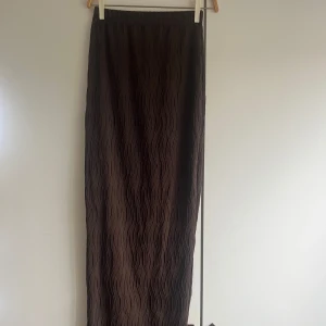 Långkjol med vågig struktur - Brun långkjol med vågig struktur i tyget. Kjolen har en tajt passform och har resår i midjan. 