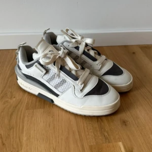 Adidas sneakers  - Snygga Adidas sneakers i vitt och grått med coola meshdetaljer på sidorna och klassiska ränder. Skorna har snörning, platt sula och en mix av skinn och syntetmaterial. Perfekta för dig som gillar en sportig och stilren look. Endast använda en gång. 