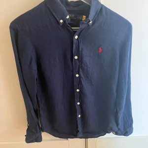 Marinblå linneskjorta från Polo Ralph Lauren - Snygg marinblå skjorta från Polo Ralph Lauren i linne med klassisk krage och vita knappar 