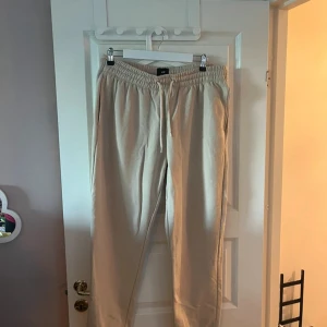 Beiga mjukisbyxor med snörning - Snygga beiga mjukisbyxor med elastisk midja och snörning. Perfekta för chill dagar eller när du vill vara bekväm. Byxorna har en avslappnad passform och är gjorda i mjukt material.