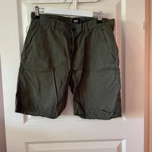 Mörkgröna shorts från 157 - Snygga mörkgröna shorts från 157 med klassisk passform och sidfickor. Perfekta för varma dagar, tillverkade i mjuk bomull som känns skön mot huden. Stängs med knapp och dragkedja framtill. Enkla att matcha med t-shirt eller hoodie.