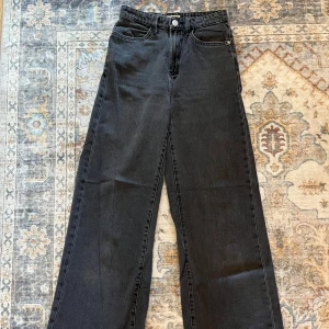 Svarta wide jeans från Lindex - Säljrr ett par svarta jeans från Lindex med raka, vida ben. Klassisk femficksmodell med dragkedja och knapp framtill. 
