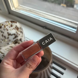 CAIA Vacay läppglans nude - Säljer ett CAIA läppglans i färgen Vacay. Glanset har en snygg nude/peachy ton med lätt skimmer och kommer i en stilren genomskinlig förpackning med silverlock. Perfekt för att ge läpparna en fräsch och glansig finish. (Endast testad)