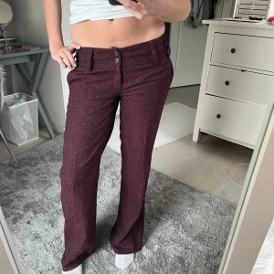 Lågmidjade vinröda kostymbyxor med raka ben - Snygga  vinröda kostymbyxor med melerad look och raka ben. Byxorna har låg midja, dubbla knappar framtill, bälteshällor och fickor både fram och bak. Perfekta för dig som vill ha en stilren men ändå chill vibe. Långa i benen jag är 175