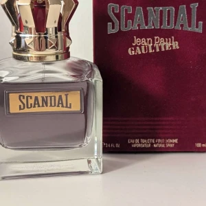 Scandal Pour Homme EdT Jean Paul Gaultier - Ca 90 ml kvar                                                         Scandal Pour Homme från Jean Paul Gaultier är en eau de toilette för män. Flaskan är fyrkantig i tjockt glas med en lyxig guldfärgad krona som lock. Parfymen har en mörklila ton och etiketten är guldig med svart text. Kommer i en vinröd sammetsbox.