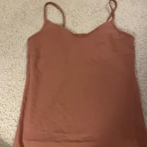 Gammelrosa linnetopp med smala axelband - Säljer en enkel och stilren gammelrosa linnetopp med smala axelband. Toppen har en mjuk v-ringning och är perfekt för varma dagar. Passar snyggt till både jeans och kjol. Färgen är varm och jordnära, vilket gör den lätt att matcha.