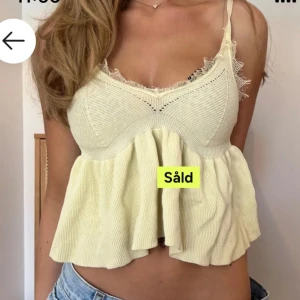 Ljusgul stickad topp från Zara - Supersöt ljusgul stickad topp från Zara med volang nertill och spetsdetaljer vid v-ringningen. Tunt ribbat material och justerbara axelband 