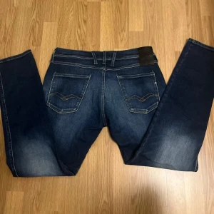 Mörkblå jeans från Replay - Snygga mörkblå jeans från Replay i modellen Anbass. De har en klassisk femficksdesign med dragkedja och knapp framtill. Perfekta för en stilren look.                   Väldigt bra skick, inga defekter eller skador!