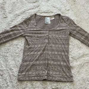 Beige mönstrad långärmad pyjamas tröja H&M - Superfin beige långärmad pyjamas tröja från H&M med coolt geometriskt mönster i vitt. Tröjan har rund halsringning och knappar framtill. Tillverkad i mjuk bomullsblandning med polyester och lite stretch för extra komfort.