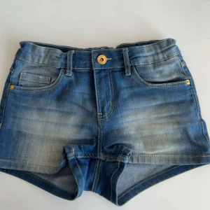 Blå jeansshorts  - Snygga blå jeansshorts från LAB Industries med klassisk femficksdesign, gylf med guldfärgad knapp och bälteshällor. Shortsen har en lätt tvättad look och är perfekta för varma dagar. De är korta i modellen och har en ganska tajt passform. Ord pris 199kr 