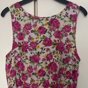Blommig playsuit  - Superfin playsuit från Rut&Circle med färgglatt blommönster i rosa, gult och grönt på vit botten. Ärmlös modell med rund hals. Perfekt för sommarens alla tillfällen!