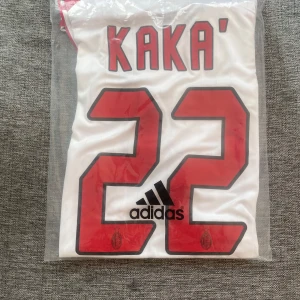 AC Milan Kaka 22 Champions League tröja - AC Milan bortatröja från Champions League-finalen 2007 med Kaka och nummer 22 på ryggen. Vit med röda och svarta detaljer, broderat klubbmärke och Adidas-logga. Tillverkad i lätt och ventilerande material, Formotion-teknologi. Klassisk passform och korta ärmar.