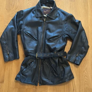 Svart skinnjacka - Snygg svart äkta skinnjacka från Roco Baroco med bälte i midjan och dragkedja framtill. Väldigt bra skick, endast liten defekt som knappt är märkvärdigt (bild4) skulle säga storleken är M pris kan diskuteras vid snabb affär :)