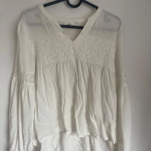 Vit blus med spets från Kappahl - Superfin vit blus från Kappahl med v-ringning och blommig spets upptill och på ärmarna. Långärmad modell med lätt puff och lös passform. Perfekt för dig som gillar romantisk och bohemisk stil. Tunn och luftig, passar till många outfits. 164 men passar storlek S också.