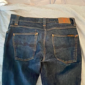Mörkblå Nudie Jeans   - Säljer ett par mörkblå jeans från Nudie Jeans i modellen Grim Tim ( Slim/Straight fit ). De är använda 2-3 gånger, var för små för mig. De är i nytt/mycket bra skick, utan defekter eller smuts. W32 : L32  
