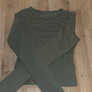 Mörkgrön långärmad topp - En stilren mörkgrön långärmad topp med rund halsringning. Modellen är enkel och tight, perfekt att matcha med jeans eller kjol. Materialet känns mjukt och stretchigt, vilket gör den bekväm att bära hela dagen.