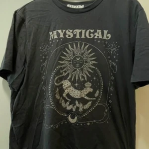 Mystical svart t-shirt från Stay - Svart t-shirt från Stay med coolt tryck av sol, måne och leopard samt texten 'MYSTICAL'. Klassisk rund hals och korta ärmar. 