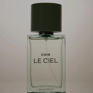CAIA Le Ciel Eau de Parfum - Fräsch parfym från CAIA i stilren, transparent glasflaska med svart cylinderformad kork. Doften heter Le Ciel och flaskan har minimalistisk design med tydlig text framtill. Perfekt för dig som gillar moderna och eleganta parfymer.