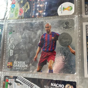 Adrenalyn XL Official Trading Card Game 2012-2013: Henrik Larsson FC Barcelona - Samlarbok med officiella Champions League trading cards från säsongen 2012-2013. Innehåller bland annat ett exklusivt kort av Henrik Larsson i FC Barcelona. Perfekt för unga fotbollsfans och samlare som vill ha en bit av fotbollshistorien.