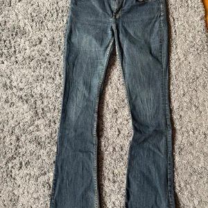 Blå bootcut jeans från Base - Snygga blå jeans från Base med klassisk bootcut-passform. Jeansen har gul kontrastsöm och mässingsfärgade detaljer. Tillverkade i mjukt denimtyg som sitter skönt. 