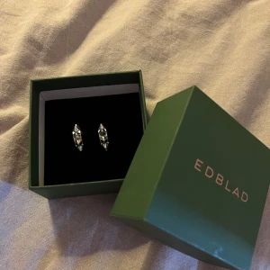 Silvriga örhängen med nitar från Edblad - Coola silvriga örhängen från Edblad med nitar runt hela ringen. Perfekta för dig som vill ha en tuff detalj till din look. Använda 2 gånger❤️🥰