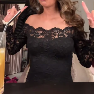 Svart spetsbody offshoulder - Säljer en svart body med offshoulder och långa ärmar i vacker spets. Toppen har en romantisk känsla med blommigt spetsmönster och figurnära passform. Perfekt för dig som vill sticka ut med en elegant och trendig look.