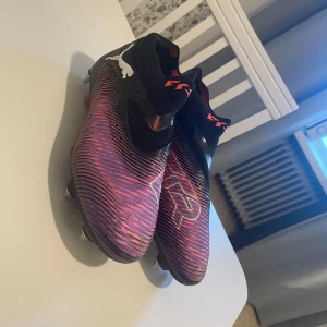 Puma Future Z fotbollsskor - Säljer ett par Puma Future Z fotbollsskor i svart och lila med orange detaljer. Ä Storlek 40 men liten i storleken så är snarare storlek 41. Nyskick använda 1gång