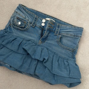 Jeanskjol med volang - Säljer en blå jeanskjol med volangdetaljer. Har sytt denna från ett par jeans! Lite små fläckar där bak men inget man tänker på, går säkert bort i tvätten. Jeansen är från Gina Young 