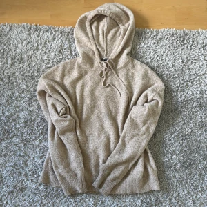  stickad hoodie - Mysig beige stickad hoodie från Lindex med huva. Tröjan har långa ärmar och ribbade muddar vid ärmslut och nederkant. Väldigt skön och få defekter ända är att den är lite nopprig. 