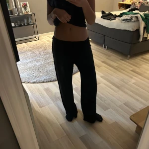 Svarta vida byxor - Säljer ett par svarta byxor med vid passform och hög midja. Byxorna har en enkel och stilren design utan synliga detaljer och passar perfekt till en avslappnad look.