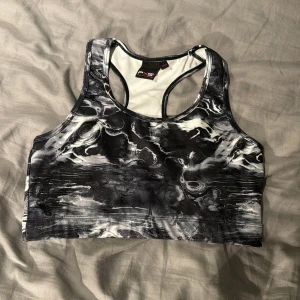 Svart och vit sport-bh från Phelix Sports - Säljer en sport-bh från Phelix Sports med svart och vit abstrakt mönster. Modellen har brottarrygg och är tillverkad i ett stretchigt material som passar perfekt för träning. Snygg och bekväm design!