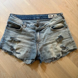 Ljusblå jeansshorts från Crocker - Ljusblå jeansshorts från Crocker med råa kanter och slitna detaljer framtill. Klassisk femficksmodell med knapp och dragkedja. Perfekta för sommaren!