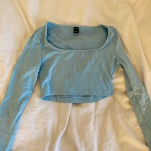 Ljusblå croppad långärmad topp från SHEIN - Säljer en ljusblå croppad långärmad topp från SHEIN i ribbat material. Toppen har en fyrkantig urringning och sitter tight. Perfekt att styla med höga jeans eller kjol. I storlek Petite xs