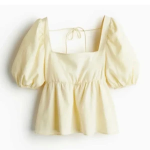 Gul puffärmad blus med knytband - Söt ljusgul blus med puffärmar och fyrkantig ringning. Blusen har knytband i ryggen och resår i midjan för en feminin siluett. Perfekt för vår och sommar, och ger en romantisk känsla till outfiten.